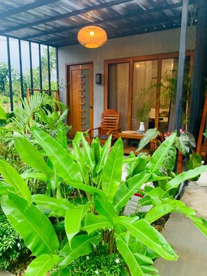 Un espacio al aire libre techado con una silla de madera, una mesa y un colgador de luz.