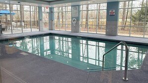 Una piscina interior con paredes de vidrio transparente, suelo de baldosas y un cartel de advertencia para socorristas.