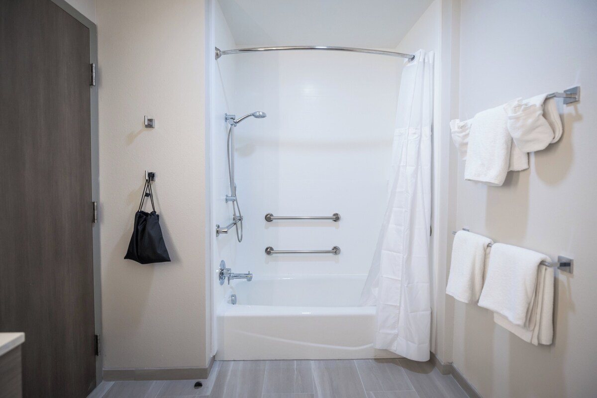 A modern bathroom with a walk-in shower, grab bars, and a towel rack.
