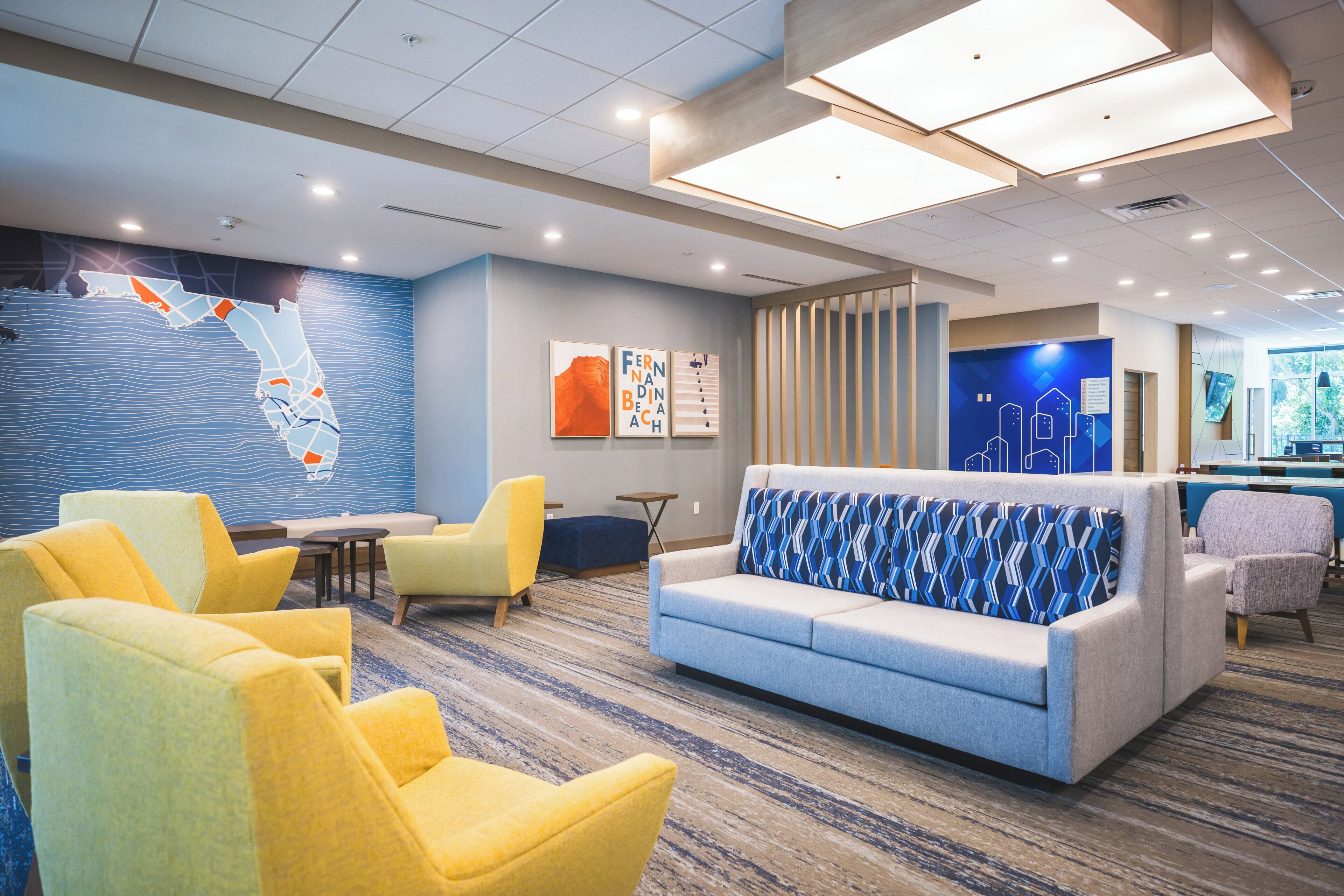 Un vestíbulo de hotel con zona de estar, un mural de mapa y un mostrador de recepción.