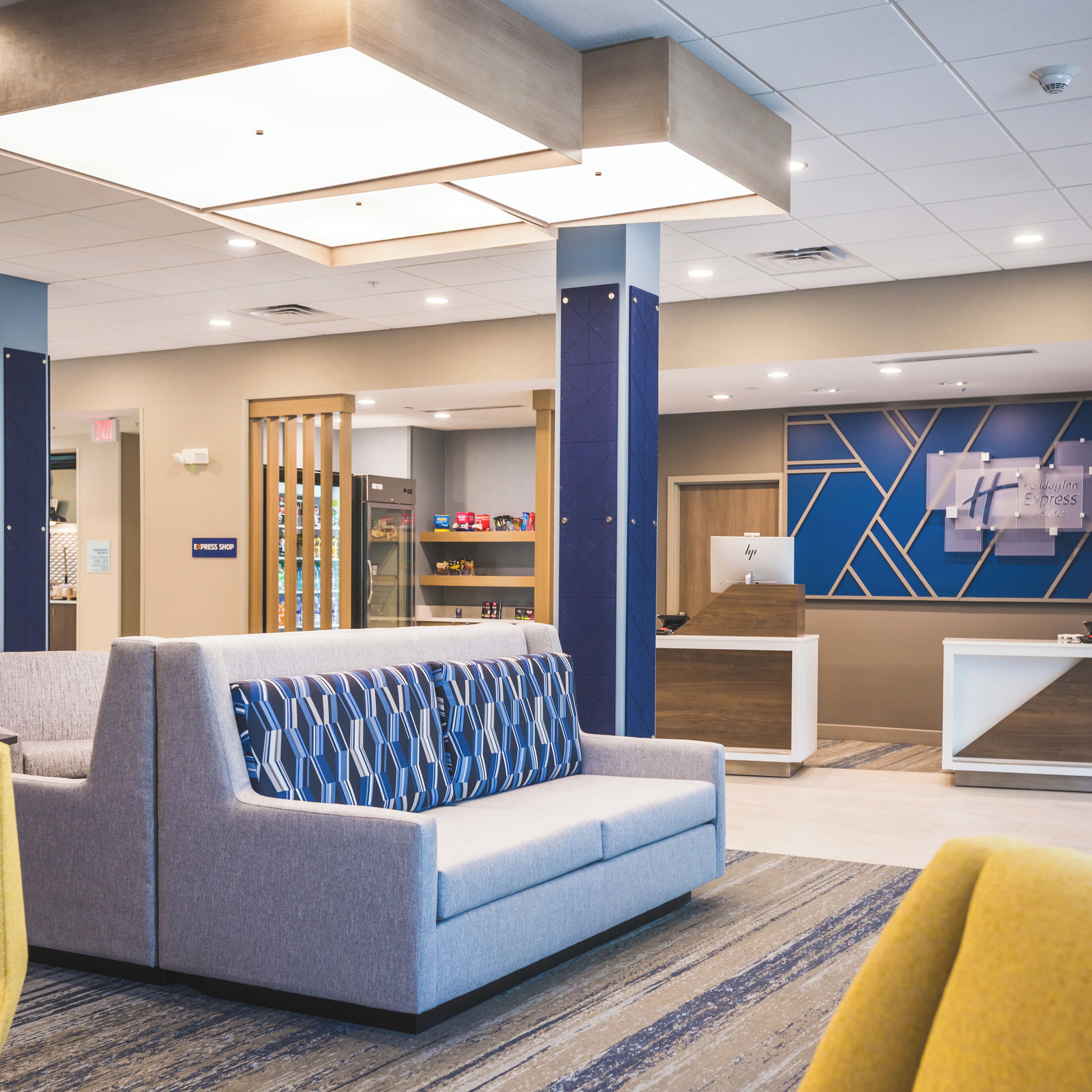 A hotel lobby with a reception desk, seating area, and a kitchenette.
