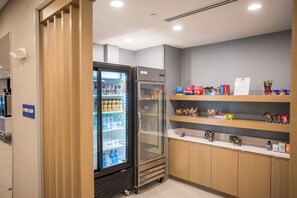 A hotel room with a minibar, a refrigerator, and shelves stocked with snacks and beverages. - Holiday Inn Express & Suites Fernandina Beach Amelia Island by IHG (Fernandina Beach)