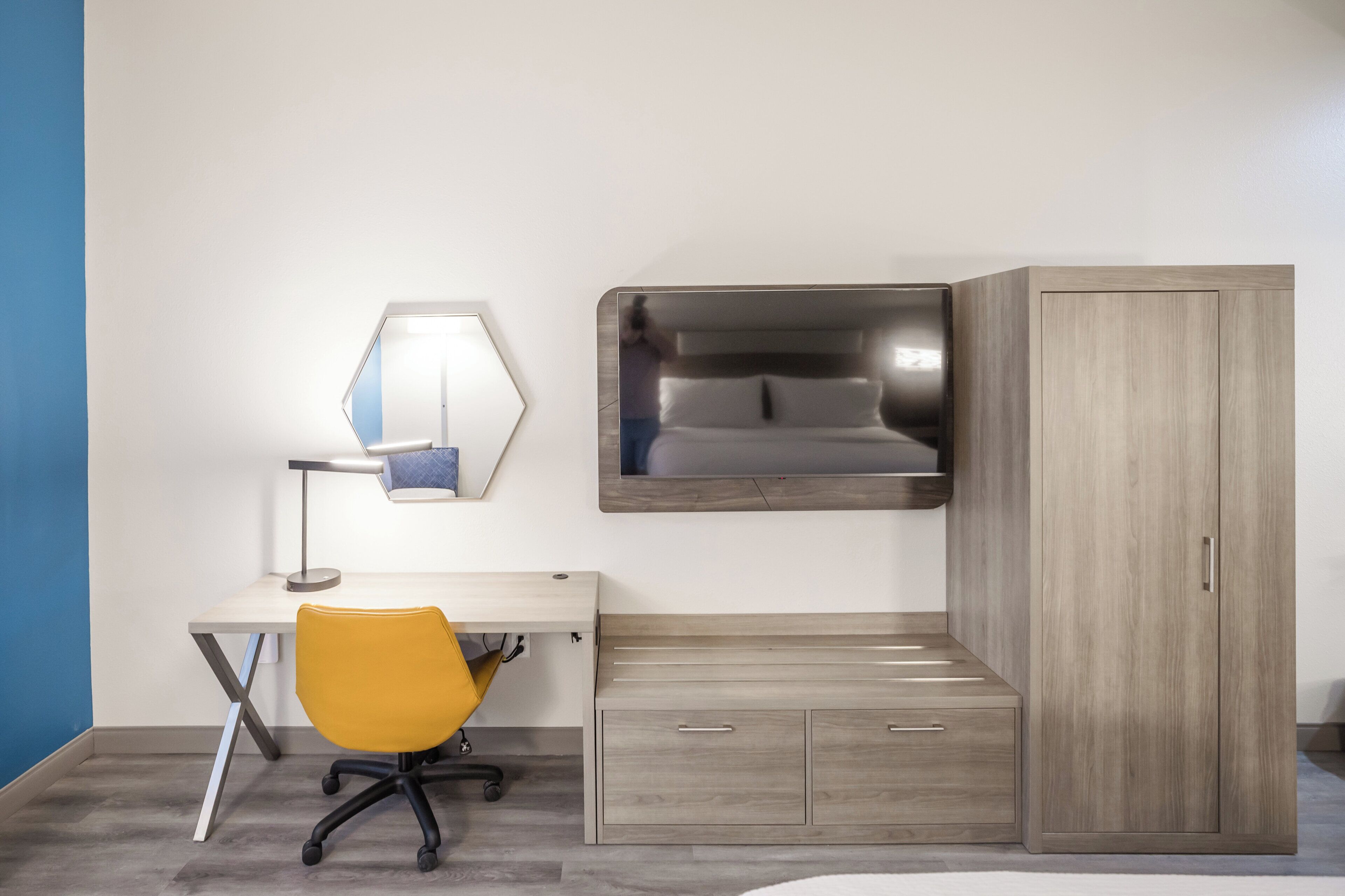 A room with a desk, a chair, a wardrobe, and a bed.