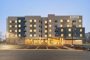 A multi-story Staybridge hotel with a modern design, featuring a central entrance, a parking lot, and a well-lit facade. - Staybridge Suites Norfolk Airport by IHG (Norfolk)