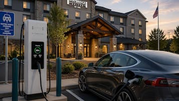 An electric vehicle charging station at a hotel with a stone facade and a covered entrance.