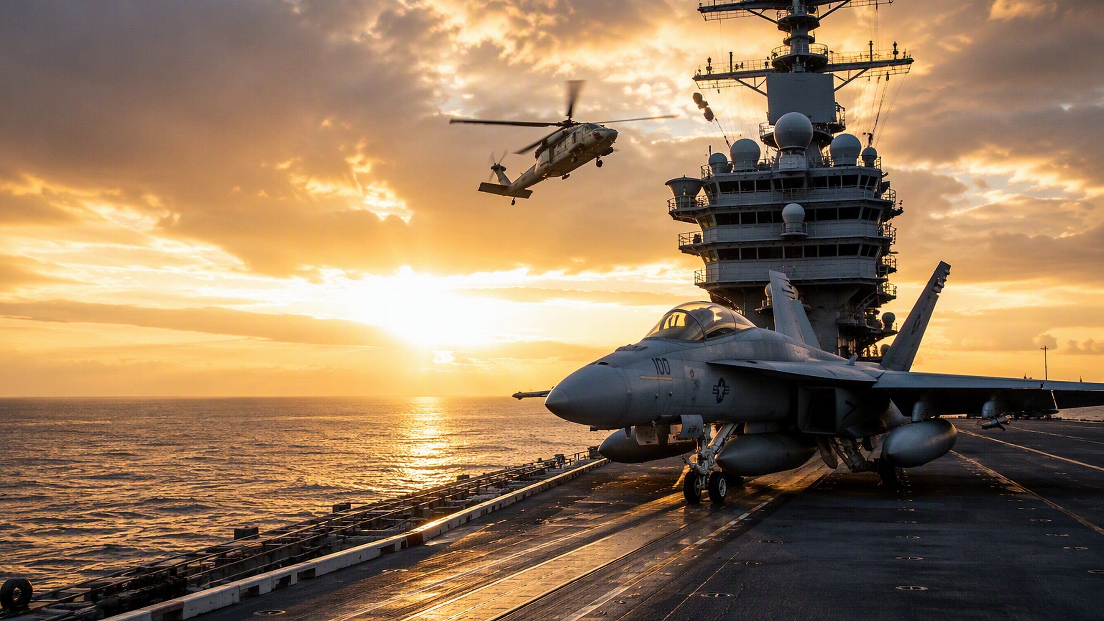 An aircraft carrier with a fighter jet and a helicopter on deck during sunset.