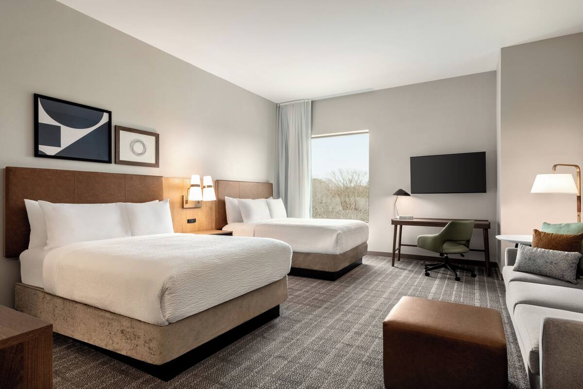 Une chambre d’hôtel avec deux lits, un bureau, une télévision et un canapé.