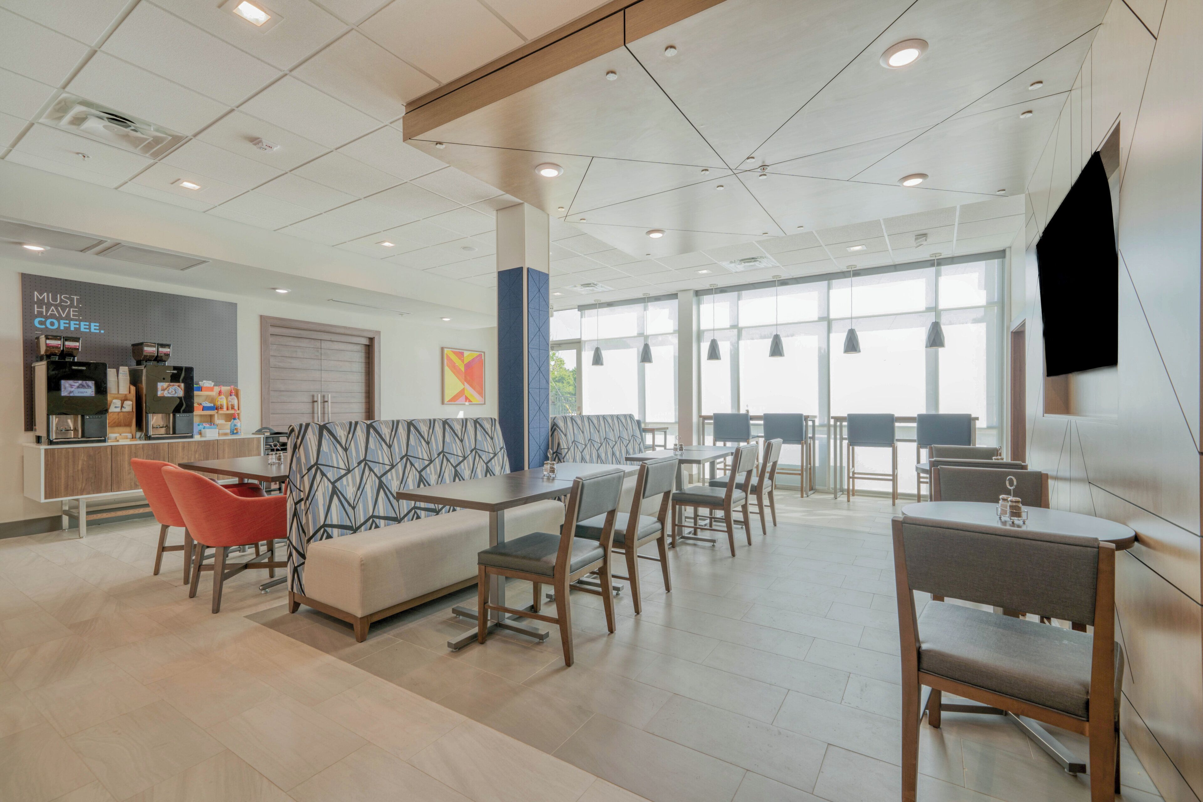 A modern interior with seating areas, a coffee station, and large windows.