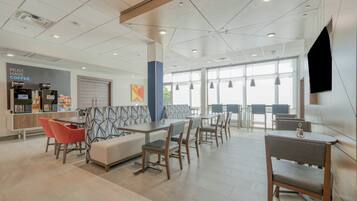 A modern interior with seating areas, a coffee station, and large windows.
