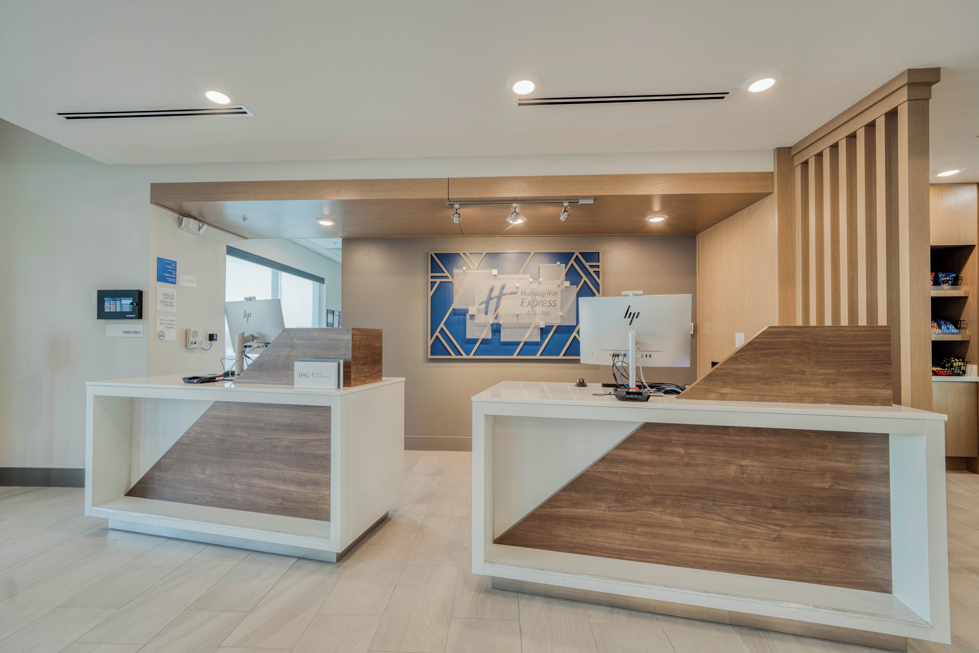 A reception area with two reception desks, a staircase, and a blue geometric wall art piece.