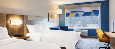 Une chambre d’hôtel avec deux lits, un bureau et une chaise.