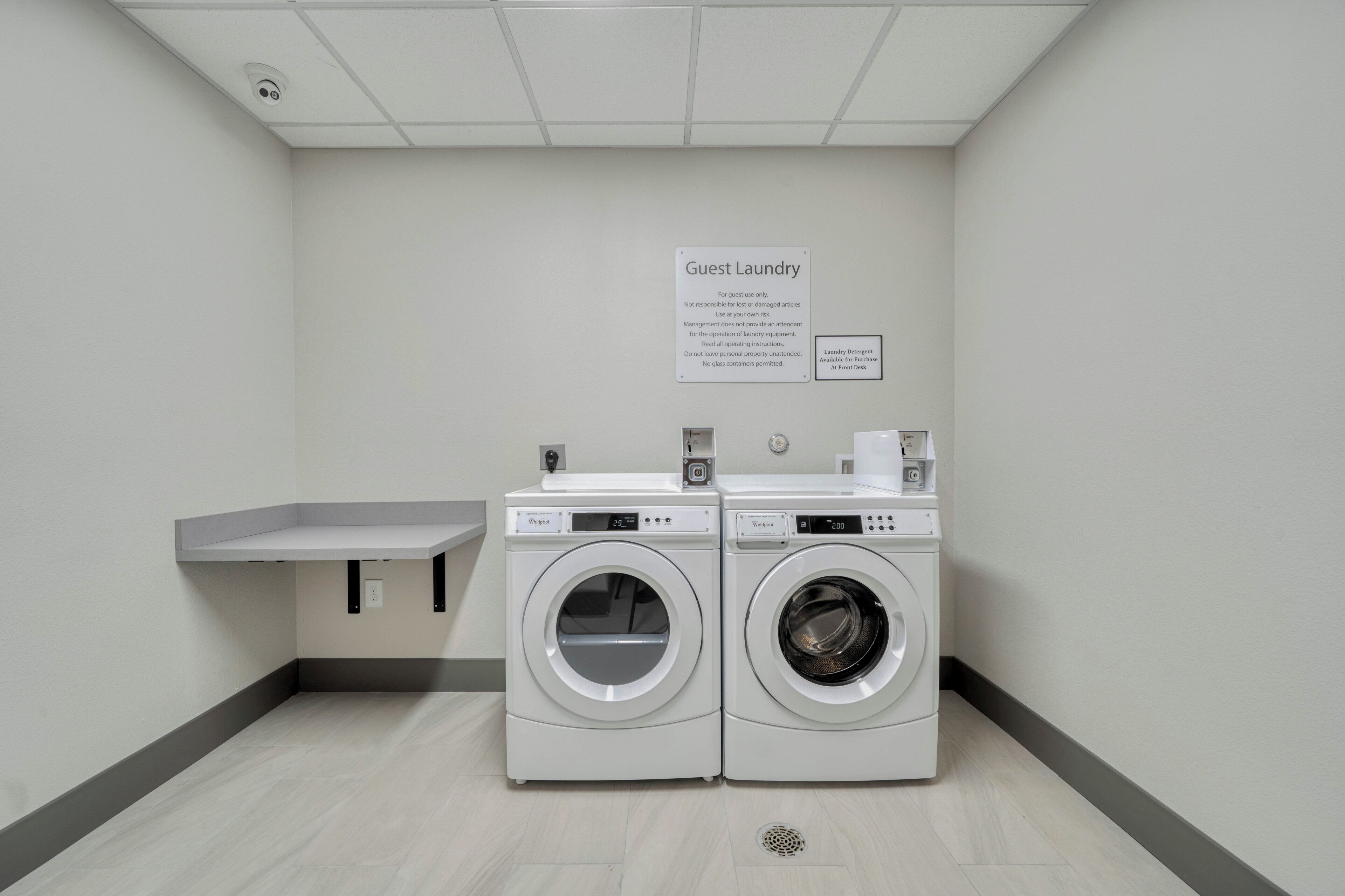Zona de lavandería para huéspedes con dos lavadoras Whirlpool de carga frontal, un lavamanos y un letrero que indica que es solo para uso de huéspedes.
