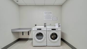 Zona de lavandería para huéspedes con dos lavadoras Whirlpool de carga frontal, un lavamanos y un letrero que indica que es solo para uso de huéspedes.
