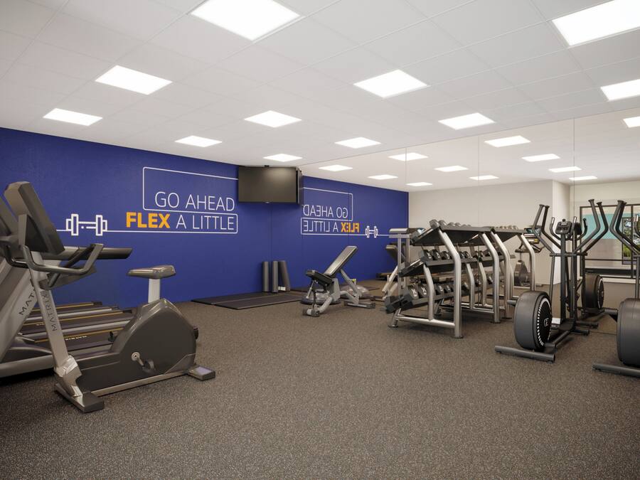 Une salle de sport équipée de divers appareils d’exercice, ornée de citations motivantes sur les murs et dotée d’un mur entièrement recouvert de miroirs.