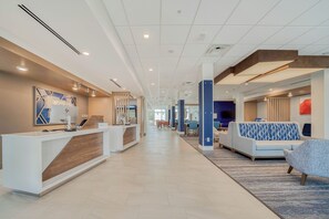 A hotel lobby with a reception desk, seating area, and a view of the corridor. - Holiday Inn Express Tyler South University Area by IHG (Tyler)