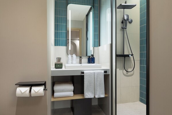 A modern bathroom with a sink, mirror, and shower.