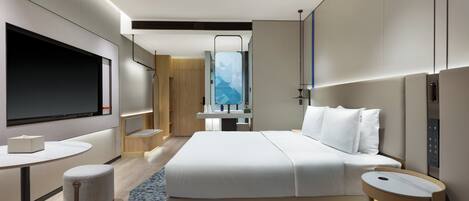 A modern hotel room with a large bed, a desk, a television, and a bathroom with a mirror and sink.