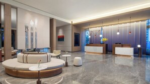 Un vestíbulo moderno con una zona de estar circular, una recepción y un amplio ventanal con vistas.