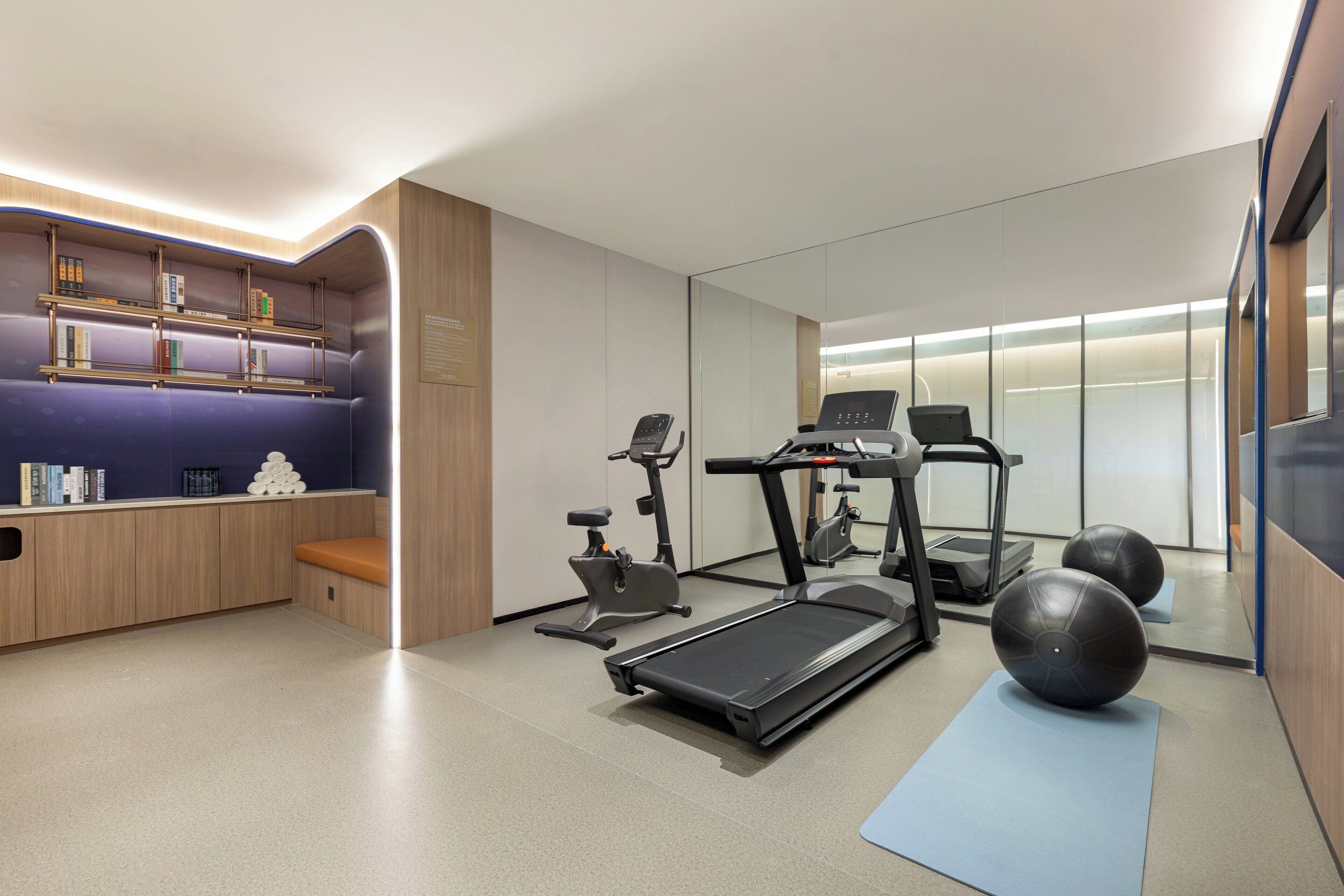 A modern fitness room with a treadmill, exercise balls, and a bench.