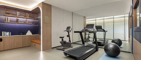 A modern fitness room with a treadmill, exercise balls, and a bench.