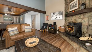 Un salon chaleureux avec une cheminée en pierre, un canapé en cuir et une table basse en bois.