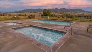 Une piscine divisée en deux zones distinctes, entourée d’une terrasse en béton, avec un paysage montagneux en arrière-plan.