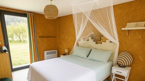 Un dormitorio con cama, mesita de noche y ventana con cortinas.