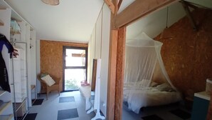 Un dormitorio con cama con dosel, un armario, una silla y un ventanal grande.