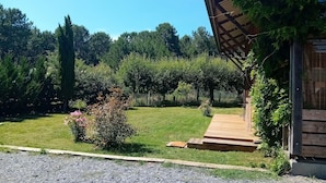 Un camino de grava que conduce a una terraza de madera con un porche cubierto.