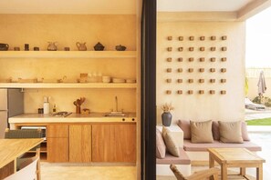 Eine moderne Küche mit Holdekor-Schränken, einer Arbeitsplatte und einem Spülbecken. Ein Essbereich mit Tisch und Stühlen lädt zum Verweilen ein. Eine Wandregal präsentiert verschiedene Küchenutensilien.