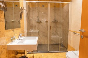 Un baño moderno con ducha envuelta en vidrio, lavamanos blanco y retrete.