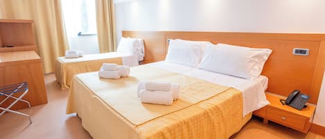 A hotel room with two beds, a desk, a chair, and a phone on a bedside table.