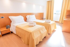 A hotel room with two beds, a wooden headboard, a bedside table with a phone, and a window with curtains. - HOTEL PLANET INTERNATIONAL (Arezzo)