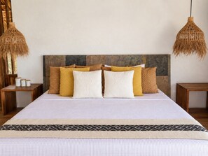 A bed with a white bedspread and multiple pillows, flanked by two nightstands with woven lamps.
