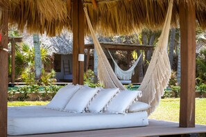 A hammock bed with white cushions in a tropical setting.