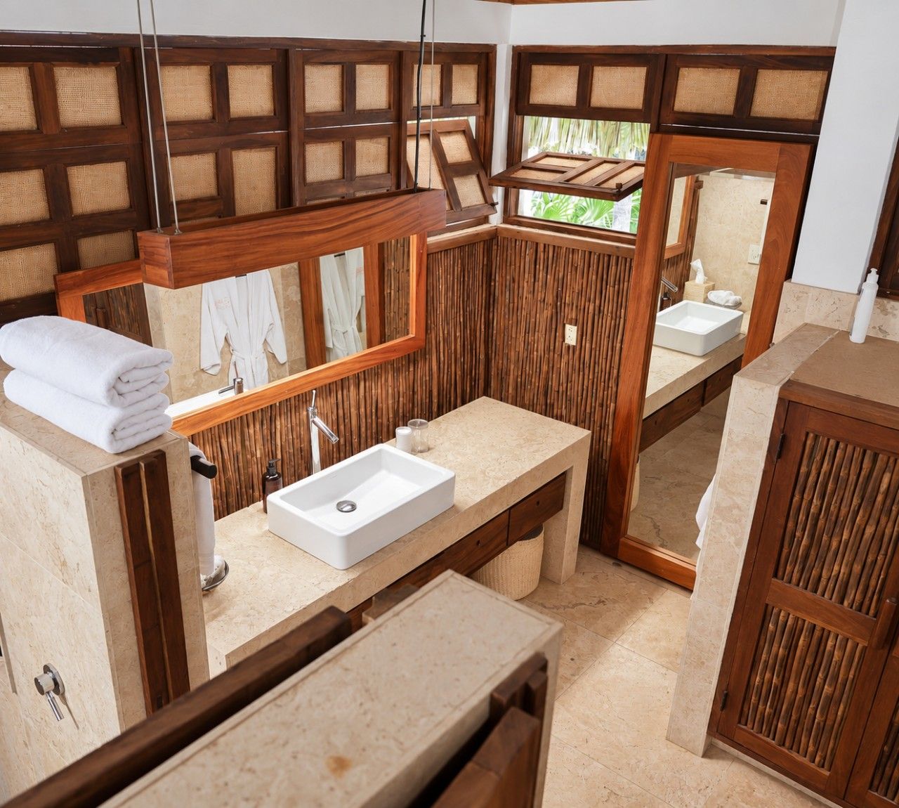 A bathroom with a large mirror, two sinks, a towel rack, and a wooden panel wall.