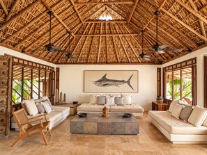 A room with a thatched roof, a sofa set, a coffee table, and a wall-mounted artwork.