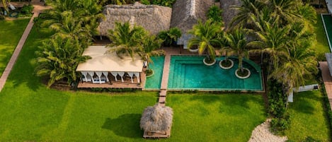 Ein Resort mit Schwimmbad, strohgedeckten Gebäuden und Palmen.