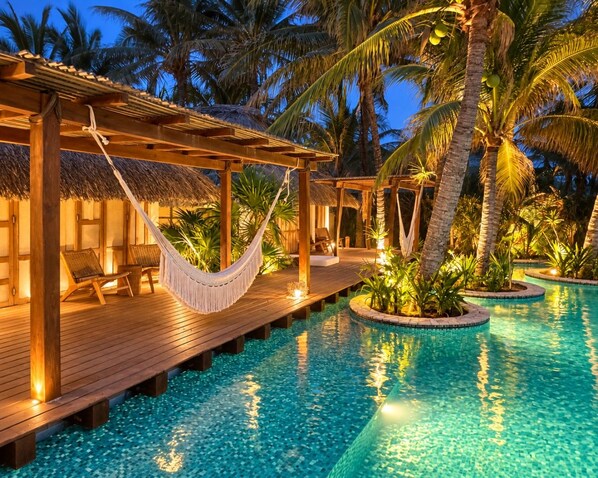 A poolside area with wooden deck, lounge chairs, and a hammock.