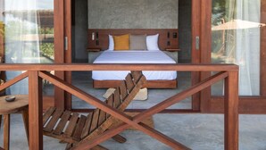 Ein Schlafzimmer mit einem Bett, einem Holzkopfende und Blick durch eine Glastür.
