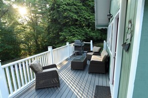 A deck with wicker furniture and a grill, surrounded by a white railing and greenery. - Summer Escape in the White Mountains (Bartlett)