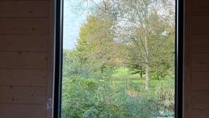 Ein Zimmer mit großem Fenster, Holzwänden und einer möblierten Betttdecke.