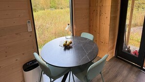Ein runder Esstisch mit zwei Stühlen, einer kleinen Tischlampe und einer Obstschale.
