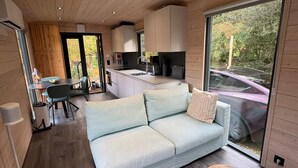 Ein modernes Interieur mit einer Couch, einem kleinen Holzschemel und einer Küchenzeile.