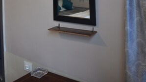 Een kamer met een grote spiegel aan de muur, een lamp boven de spiegel en een klein plankje eronder.