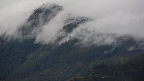 Een bergachtig landschap met weelderige begroeiing en een bewolkte lucht.