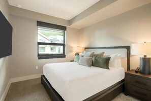 A bedroom with a large bed, bedside lamps, a window, and a view of a house. - Kindred Resort Luxury Ski In, Ski Out 1 Bedroom Residence at the River Run Gondola (Keystone)