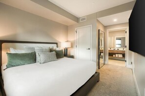 A hotel room with a large bed, a bedside table with a lamp, a wardrobe, and a mirror. - Kindred Resort Luxury Ski In, Ski Out 1 Bedroom Residence at the River Run Gondola (Keystone)