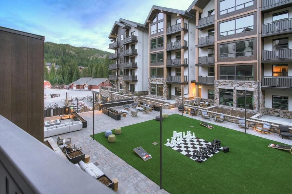 Un patio de hotel con mobiliario exterior, una mesa de ajedrez y vistas de las montañas circundantes.