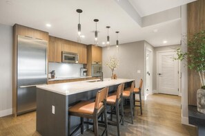 Una cocina moderna con una isla central, electrodomésticos de acero inoxidable e iluminación colgante.